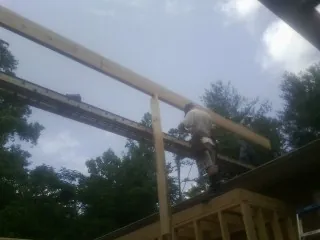 Carpenter setting a ridge beam over a new addition frame — Ice Dam Removal by Roofing Brothers in Angier