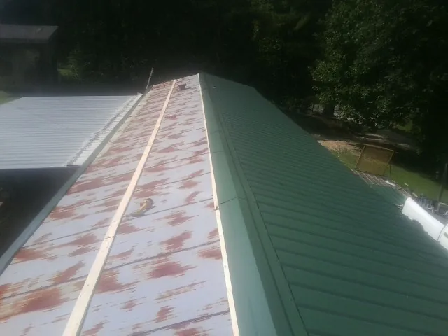 Old rusted panels beside newly installed green metal roofing — Wind Damage Roof Repair by Roofing Brothers in Angier