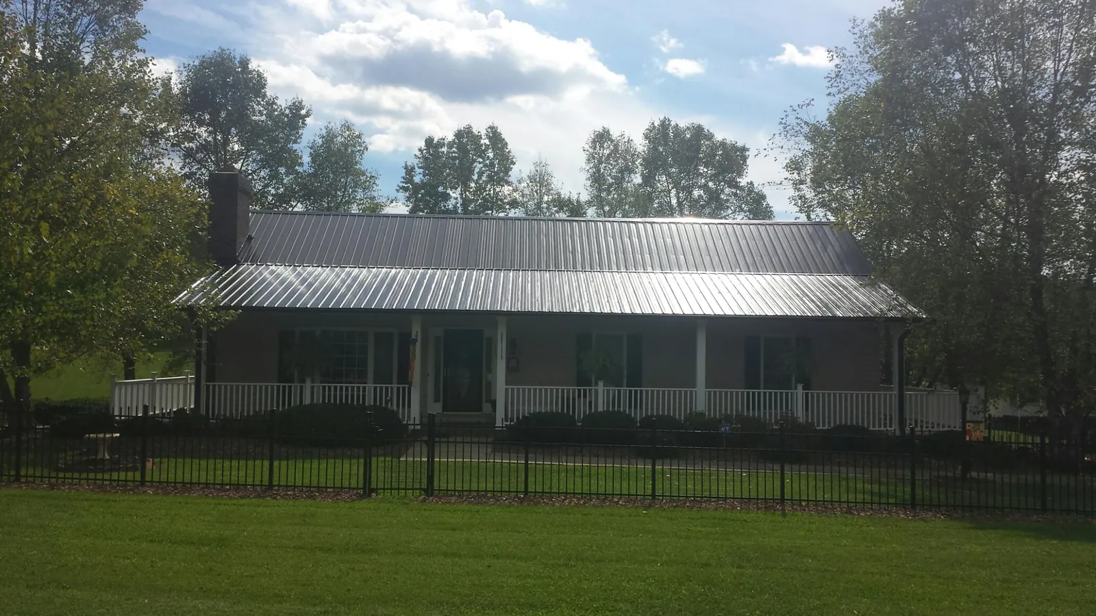 Gray metal roof on a brick ranch with a full width front porch — Gutter Guard Installation work by our crew in Angier